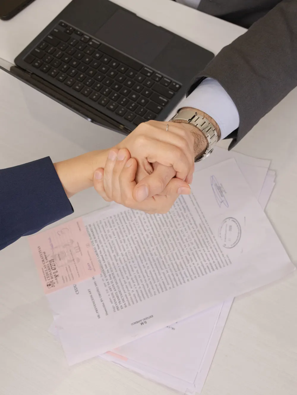 Dos personas se dan la mano sobre documentos de un reclamo ante la ART